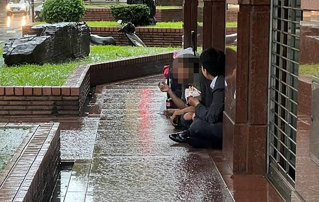 西裝男在雨天與遊民席地而坐分享餐點，在社群平台掀起討論。（拍攝者授權使用）