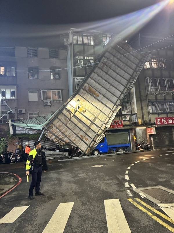 颱風康芮襲台，新北市新莊區仁愛街31日晚間有大片 鐵皮屋頂遭強風吹落後，整片緊貼公寓大樓外牆，警 方獲報到場協助引導交通，警示用路人。 （翻攝照片） 中央社記者高華謙傳真 113年10月31日