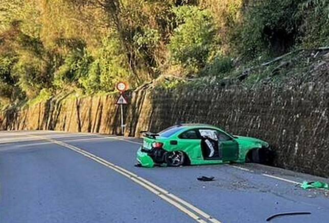 南投台十四甲線近翠峰路段，昨日發生綠色BMW雙門跑車失控撞山壁後橫在車道上，車身、車尾受損，安全氣囊爆開。（記者陳金龍翻攝）