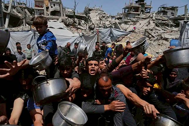 Palestinians struggle to get donated food at a community kitchen in Beit Lahia, northern Gaza Strip, May 3, 2025. (AP Photo/Jehad Alshrafi)