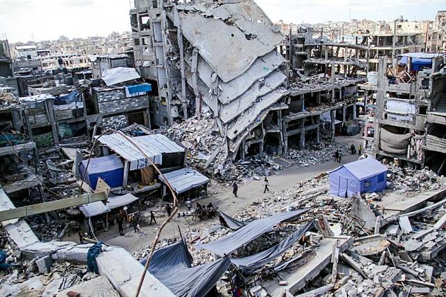 People walk on a street amid the rubble of destroyed buildings in the northern Gaza Strip city of Jabalia, Oct. 6, 2024. (Photo by Mahmoud Zaki/Xinhua)