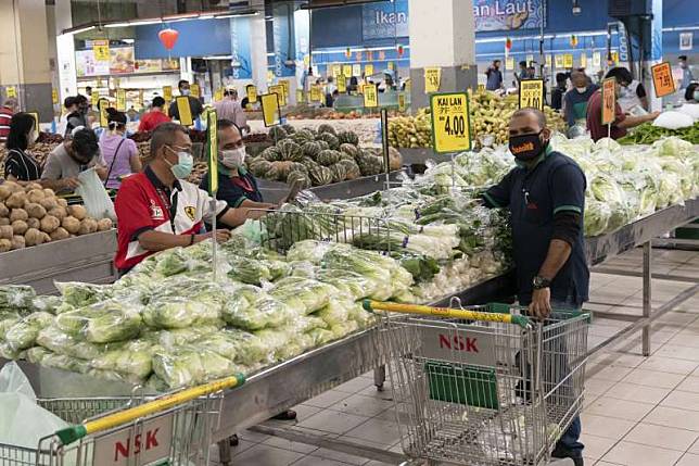 馬來西亞為防疫限制人民活動，但出門購物的男性一家之主卻不識蔬果，連超市都看不下去。（AP）