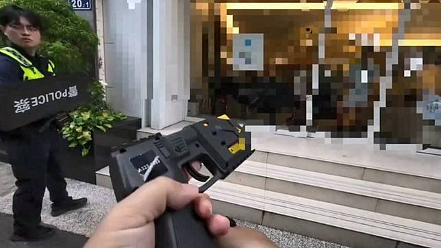 警員手持臂盾在旁防護，另名警員拿出電擊槍伺機攻擊。民眾提供