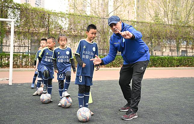 Spanish coach Pedro Jose Noguera Lopez (1st R) gives instructions to young football players at Tianjin Foreign Languages School Nanpu Primary School in Tianjin Municipality, north China, April 10, 2024. (Xinhua/Sun Fanyue)