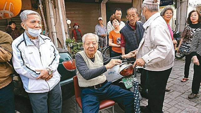 台南新化老街泰香餅鋪老闆周昭安（坐者）從火警逃生，驚魂未定，鄰居街坊紛紛趕來慰問。