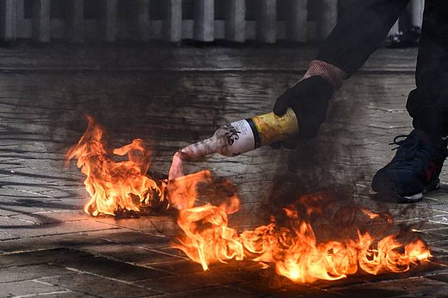 A protester lights a petrol bomb before throwing it at police stationed outside government headquarters in Hong Kong on Sunday. Photo: AFP