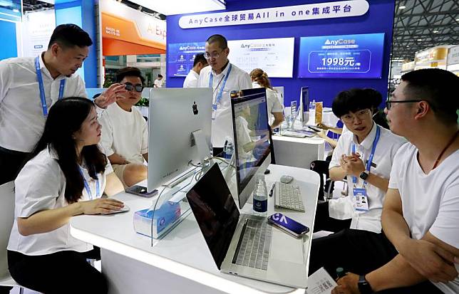 Visitors talk with exhibitors from an international trade software platform during the East China Fair in Shanghai, east China, July 12, 2023. (Xinhua/Fang Zhe)