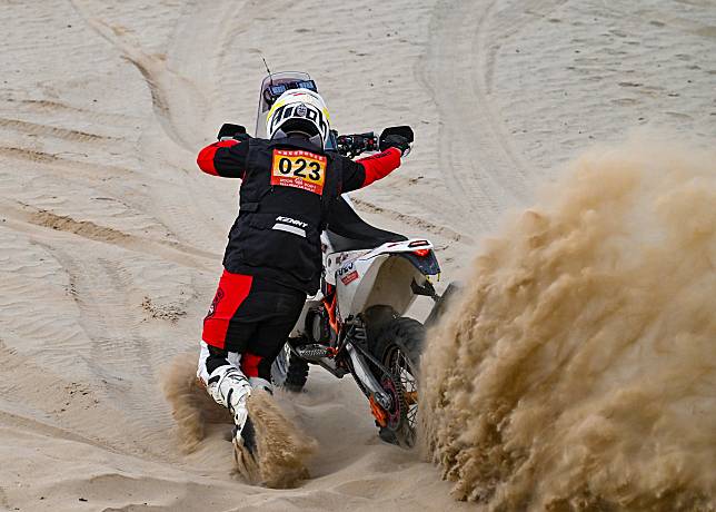 Purevdorj Murun pushes his motorcycle after it gets stuck during the Taklimakan Rally on May 23, 2024. (Xinhua/Chen Shuo)