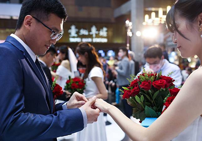 台鐵福委會三日在台北車站大廳辦集團結婚典禮，三十對新人交換誓約戒指。（中央社）