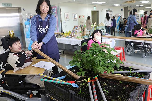 台灣園藝輔助治療協會理事長張博然利用剖開的竹筒讓翁彥如播種。（新北市社會局提供）