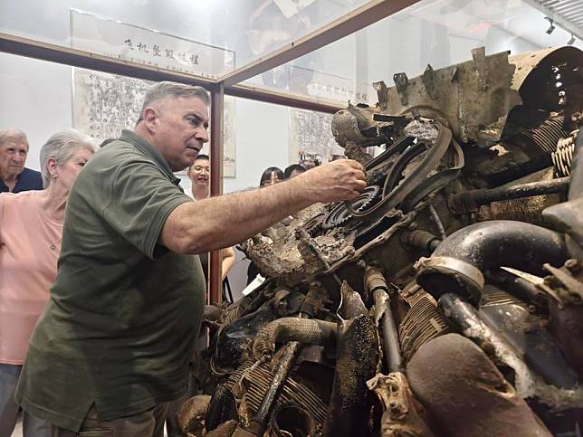 Jeffrey Greene, chairman of the Sino-American Aviation Heritage Foundation, has a touch of the wreckage from Flying Tigers bombers displayed at an exhibition in Huimin Village in Anqing City, east China's Anhui Province, Sept. 10, 2024. (Xinhua/Guo Chen)