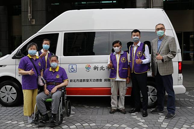 新北市道教皇天功德會委員邱鴻政（坐輪椅者）由太太陪同捐贈一輛復康巴士給新北市政府。（記者吳瀛洲攝）