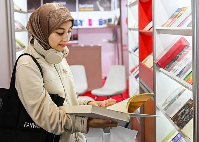 A visitor reads a book at the 41st International Istanbul Book Fair in Istanbul, Türkiye, on Nov. 2, 2024. (Xinhua/Liu Lei)