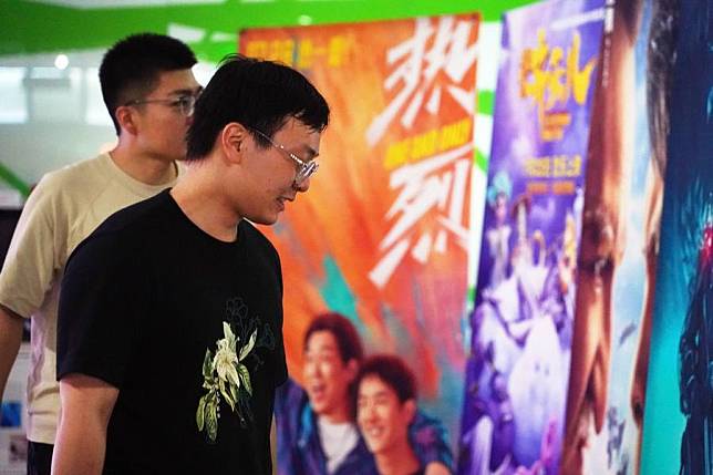 Audiences watch film posters at a cinema in Haidian District of Beijing, July 30, 2023. (Xinhua/Ren Chao)