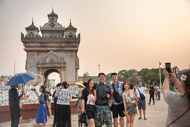 Chinese tourists take photos in front of the Patuxay monument in Vientiane, Laos, May 1, 2024. (Photo by Kaikeo Saiyasane/Xinhua)