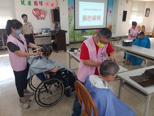 台南市美容業職業工會志工，前往北區成功養護中心，為行動不便難以外出的長輩剪髮。（勞工局提供）