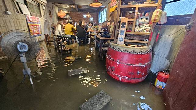 東北季風帶來豪大雨五結阿芳鹹粥民眾泡水吃飯。（記者張正量攝）