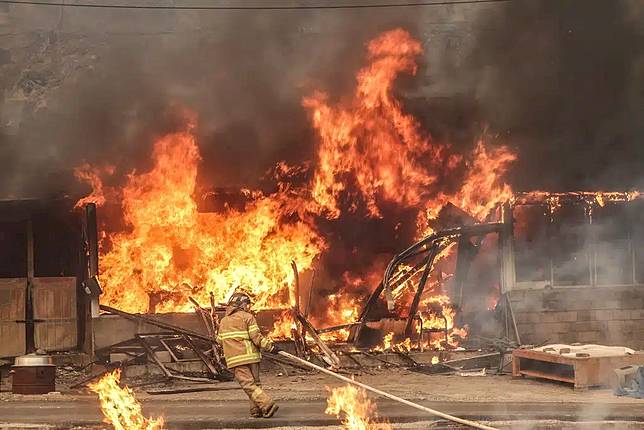 A firefighter works to extinguish a fire at a house that has been engulfed in a wildfire in Uiseong, South Korea, Tuesday, March 25, 2025. (Yoon Gwan-shick/Yonhap via AP)