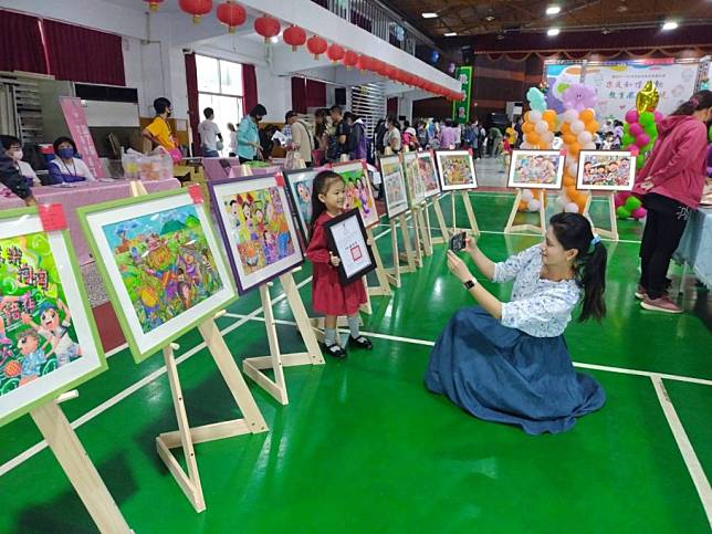 小朋友作品獲獎，家長開心拉著小孩在作品前拍照留念。（記者陳佳伶攝）