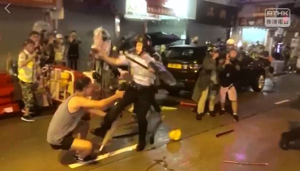 香港警察在荃葵青大遊行警民衝突中拔出左輪手槍，1名男子（左）跪求員警別開槍，卻被一腳踢開。   圖：翻攝自香港電台視像新聞 RTHK VNEWS影片