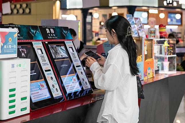 A movie goer claims tickets from a self-service machine at a cinema in Beijing, capital of China, Aug. 21, 2024. (Xinhua/Chu Jiayin)