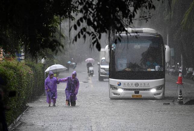 People and vehicles move through a waterlogged road in Sanya, south China's Hainan Province, Oct. 28, 2024. (Xinhua/Zhao Yingquan)