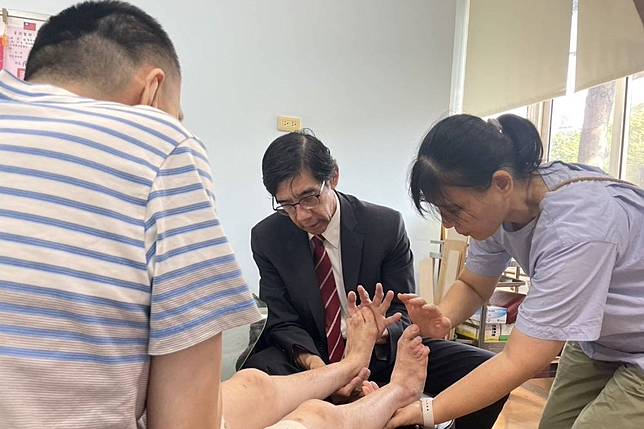 李光申醫師教導患者媽媽如何幫忙舒緩腳後跟疼痛。（瑪利亞基金會提供）