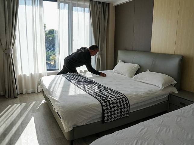 A villager tidies up a guestroom at the homestay he owns at Dong'ao Village in Wenzhou City, east China's Zhejiang Province, Nov. 27, 2024. (Xinhua/Zhang Nan)