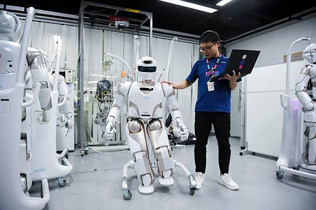 A staff member conducts tests on a Walker X humanoid robot at a sci-tech company in Shenzhen, south China's Guangdong Province, June 26, 2024. (Xinhua/Mao Siqian)