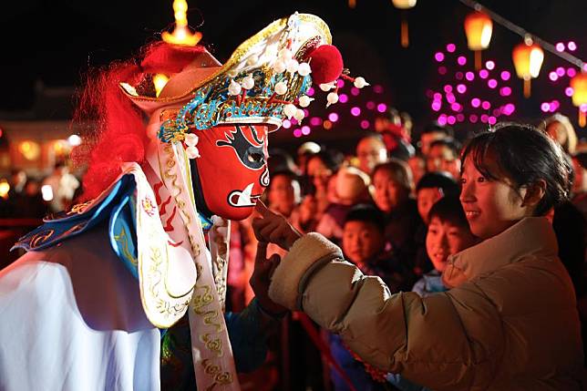 An audience interacts with a Sichuan Opera actor during a face-changing performance at a scenic spot in Qianjiang District of Chongqing, southwest China, Jan. 26, 2025. (Photo by Yang Min/Xinhua)