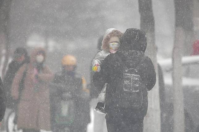 A pedestrian carries a child on a snowy day in Qiqihar, northeast China's Heilongjiang Province, Nov. 25, 2024. (Photo by Wang Yonggang/Xinhua)