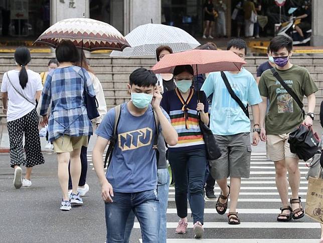 中央氣象局6日持續發布豪雨及大雨特報，受到颱風盧 碧外圍環流影響，易有短延時強降雨，台北午後下起陣 雨，民眾撐傘過馬路。 中央社記者張皓安攝 110年8月6日  
