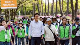 圖為2024年4月12日，首爾市長吳世勳（中）在南韓首爾永登浦區汝矣島公園，參加「第十屆首爾失智症意識步行活動」，牽著一位老年人的手。路透社資料照