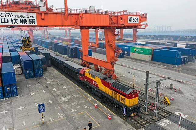 This aerial photo shows a rail-sea intermodal freight train carrying containers of goods, including cars, motorcycles, engines, and sodium carbonate, at Tuanjie Village Central Station in southwest China's Chongqing, Jan. 22, 2023. (Xinhua/Liu Chan)