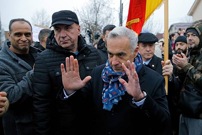 Calin Georgescu (front), winner of the first round of Romania's presidential elections, gestures after talking to the media in front of a closed polling station in Mogosoaia, near Bucharest, Romania, Dec. 8, 2024. (Photo by Cristian Cristel/Xinhua)