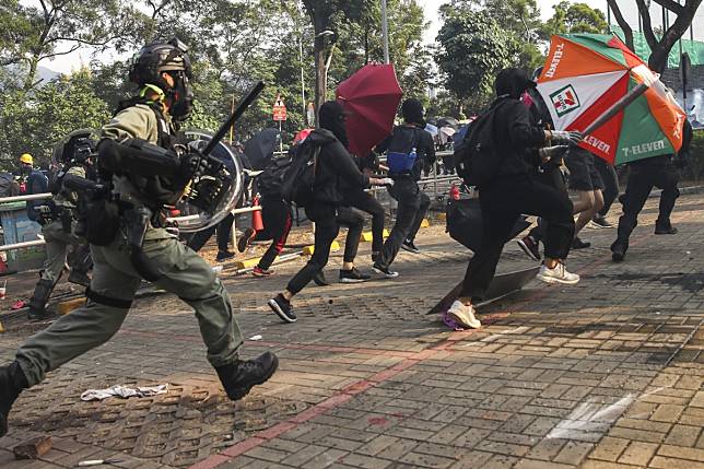 A police officer in riot gear chases protesters on the Chinese University campus. Photo: Winson Wong