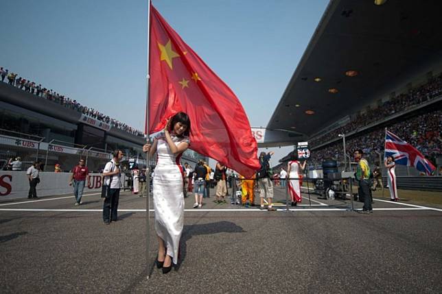 A “grid girl” holds a Chinese flag as she stands on the starting grid for the Formula One 2013 Chinese Grand Prix in Shanghai. Photo: AFP