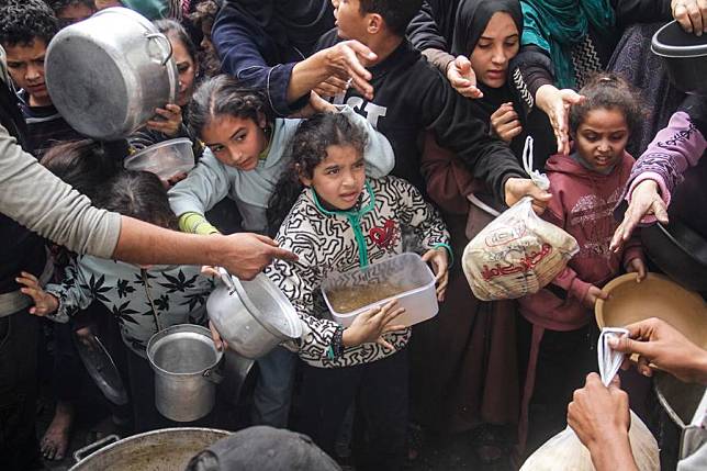 Displaced Palestinians try to get food aid from a local community kitchen amid the siege imposed by the Israeli army and the scarcity of aid in the Al-Shati camp, west of Gaza City, on Dec. 7, 2024. (Photo by Mahmoud Zaki/Xinhua)