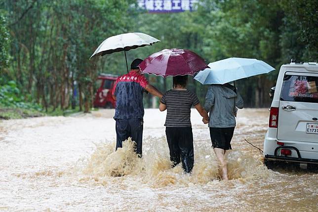 People walk on a waterlogged road in Shexian County, Huangshan City, east China's Anhui Province, June 23, 2024. (Xinhua/Du Yu)