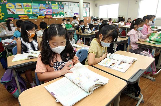 釜山的南韓小學生22日戴著口罩上課。（美聯社）