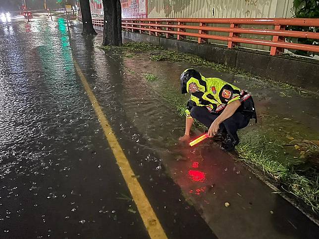 員警冒著颱風的風雨徒手清水溝。 圖：翻攝畫面