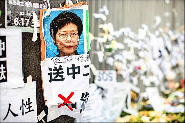 香港政府總部外的牆面被抗議民眾貼上有林鄭月娥肖像的反送中條例海報。(彭博)