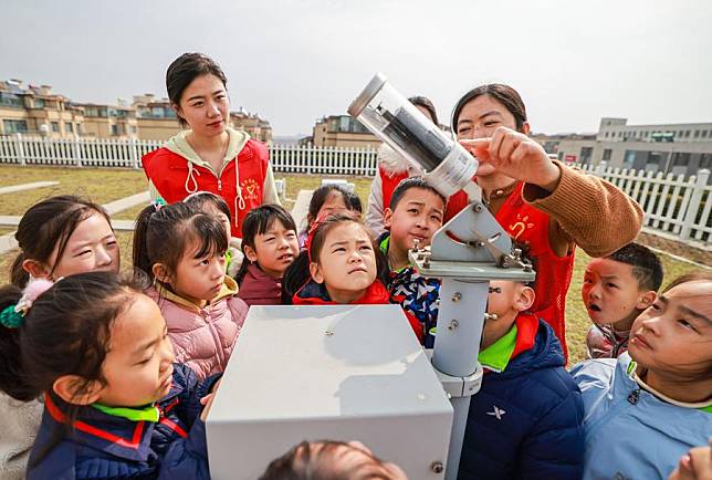 A staff member explains the working principle of a meteorological observation instrument to students at the observation field of local meteorological bureau in Rongcheng City, east China's Shandong Province, March 22, 2024. (Photo by Li Xinjun/Xinhua)