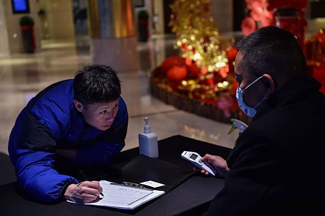 A hotel employee prepares to take the temperature of a guest about to check into a hotel in Wuhan on Friday. China has placed the city, at the centre of a deadly virus outbreak, under lockdown to contain the disease that has so far claimed 26 lives. Photo: AFP