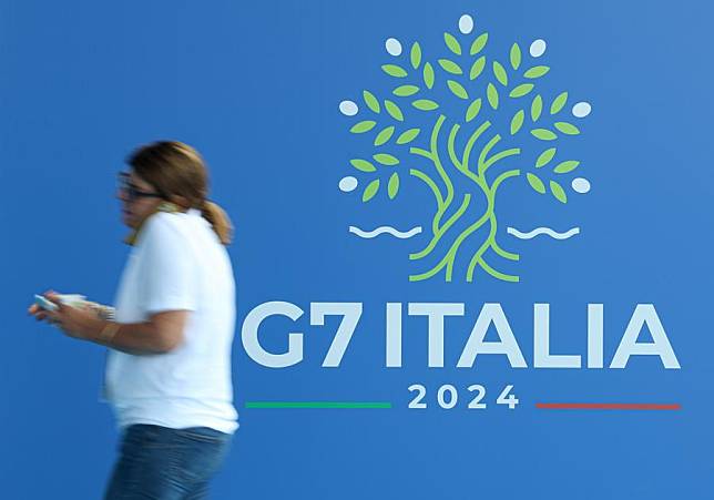 A woman walks past the banner of the Group of Seven (G7) summit at the media center in Bari, Apulia Region, Italy, June 12, 2024. (Xinhua/Li Jing)