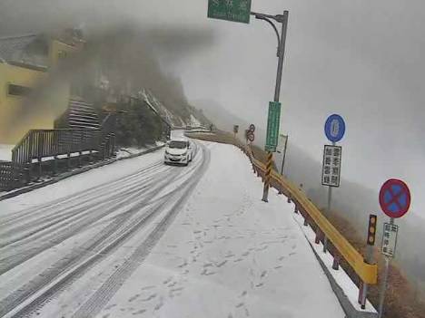合歡山在13日清晨降下瑞雪，山莊雪厚標尺、台14甲32K975公尺附近已有積雪，車輛必須加掛雪鍊才能通行。   圖：翻攝自即時影像監視器臉書影像
