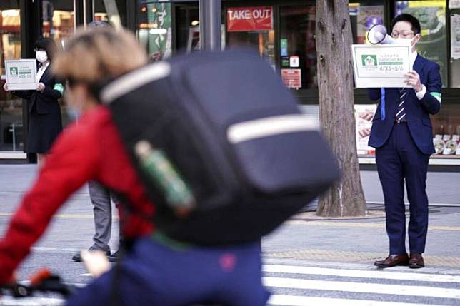 東京都政府的職員在街上呼籲民眾待在家裡，不要外出。（美聯社）