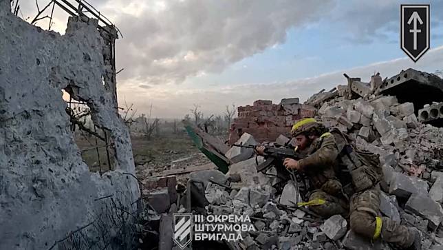 一名烏克蘭軍人16日在甫收復的安德里伊夫卡村持槍戒備。路透社