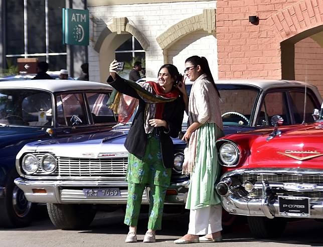 Visitors take selfies at a vintage and classic car show in Peshawar, Pakistan on Nov. 30, 2024. (Photo by Saeed Ahmad/Xinhua)