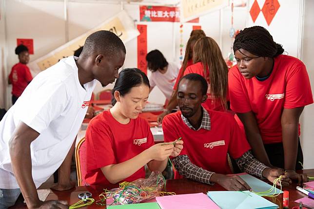 A teacher from the Confucius Institute at the University of Zambia teaches students to make Chinese knots during the 2025 Zambia-Chinese Spring Festival Temple Fair in Lusaka, Zambia, on Jan. 19, 2025. (Xinhua/Peng Lijun)